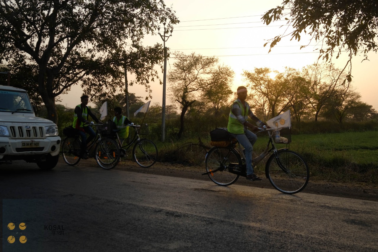 Participants in the Cycle Yatra riding along a tree-lined road at sunset